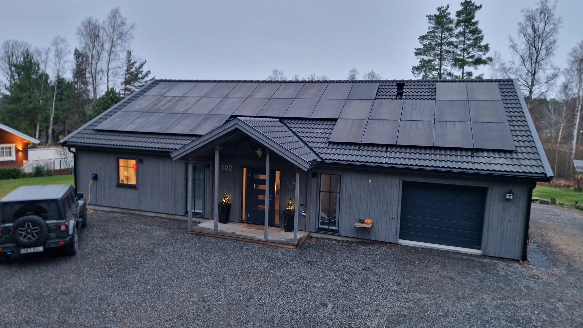 Grå villa på Hammarö med solceller på tegeltak och laddbox på fasaden